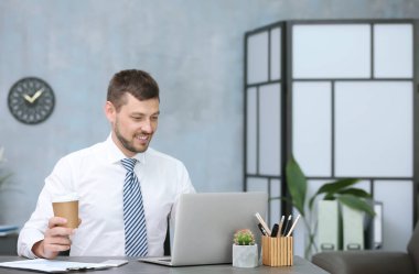 Handsome businessman drinking coffee while working in office