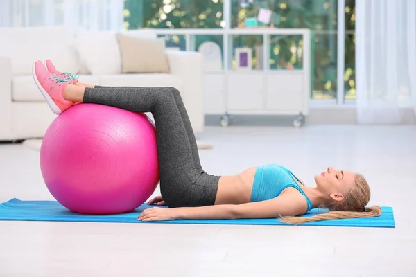 Jeune femme en vêtements de sport faisant des exercices à l'intérieur — Photo