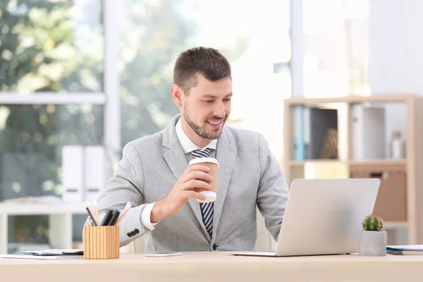 Schöner Geschäftsmann, der Kaffee trinkt, während er im Büro arbeitet — Stockfoto