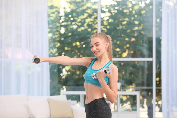 Mujer joven en ropa deportiva haciendo ejercicios en interiores —  Fotos de Stock