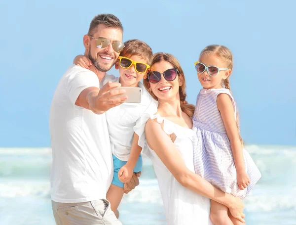 Família feliz tirando selfie na praia do mar no resort — Fotografia de Stock