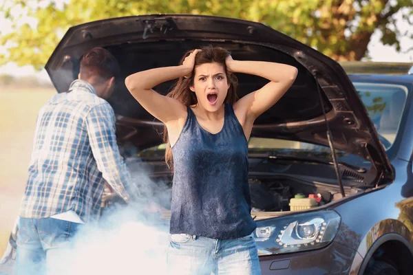 Young woman and man with broken car on background — Stock Photo, Image