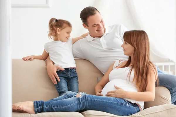 Keluarga muda yang bahagia di sofa di rumah — Stok Foto