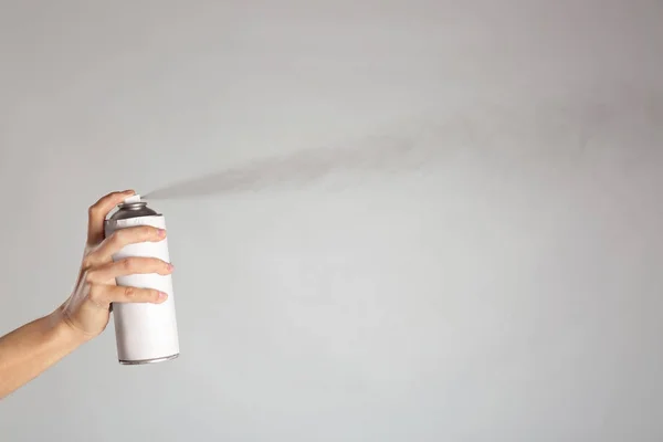 Woman spraying paint from can on light background — Stock Photo, Image