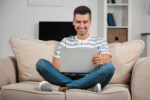 A fiatalember modern laptop otthon a kanapén — Stock Fotó