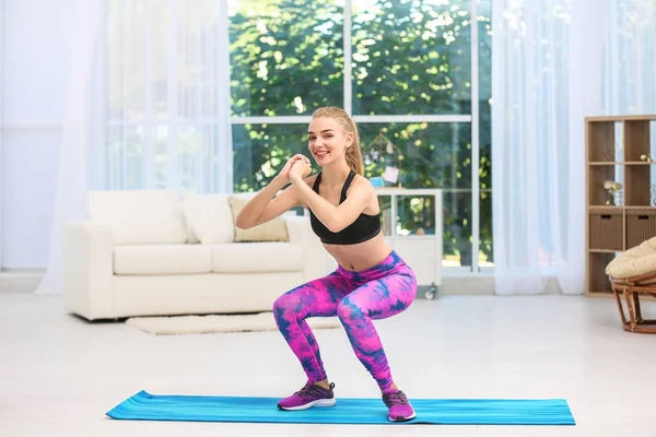 Jovem mulher em sportswear fazendo exercícios dentro de casa — Fotografia de Stock