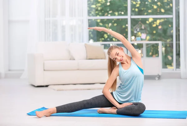 Jovem mulher em sportswear fazendo exercícios dentro de casa — Fotografia de Stock