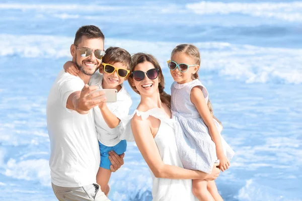 Família feliz tirando selfie na praia do mar no resort — Fotografia de Stock