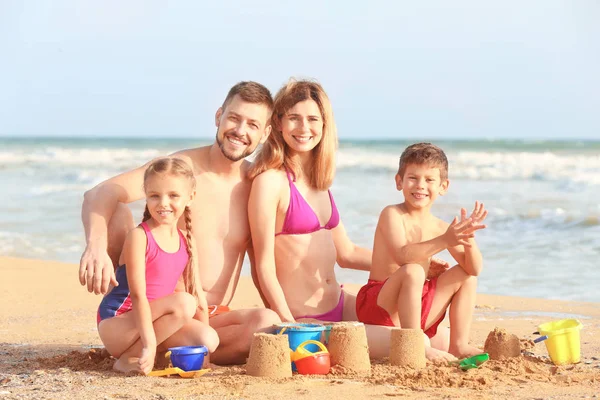 Glückliches Paar spielt mit Kindern am Strand des Resorts — Stockfoto