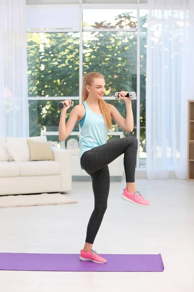 Mujer joven en ropa deportiva haciendo ejercicios en interiores —  Fotos de Stock