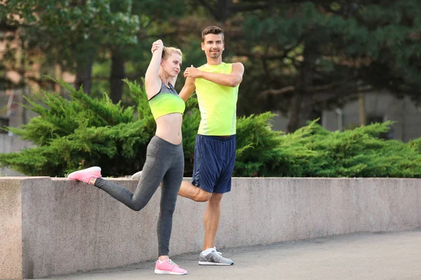 Pareja joven en ropa deportiva haciendo ejercicios en la ciudad — Foto de Stock