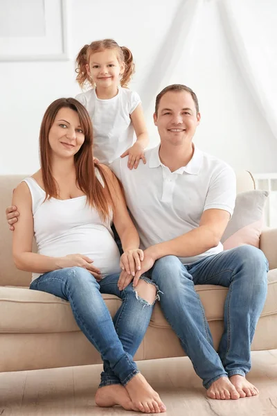 Szczęśliwa młoda rodzina na kanapie w domu — Zdjęcie stockowe