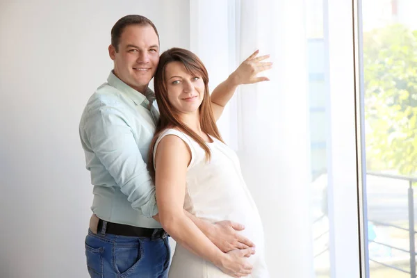 Jovem casal feliz perto da janela — Fotografia de Stock