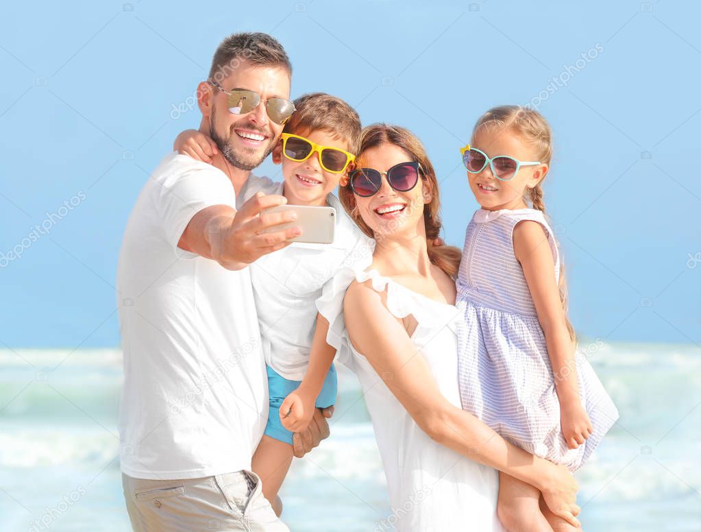 Happy family taking selfie on sea beach at resort