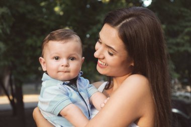 Güzel genç anne holding şirin bebek çocuk, açık havada