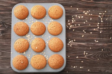 Ahşap arka plan üzerinde lezzetli yulaf ezmeli kurabiye ile fırın tepsisi