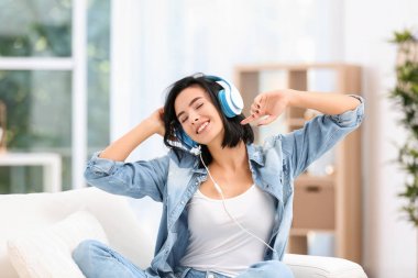 Genç kadın evde kulaklık üzerinden müzik