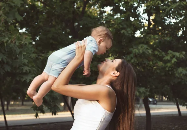 Bela jovem mãe segurando bonito bebê menino, ao ar livre — Fotografia de Stock