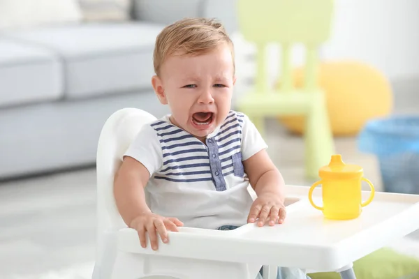 Schattig huilende baby zit in kinderstoel thuis — Stockfoto