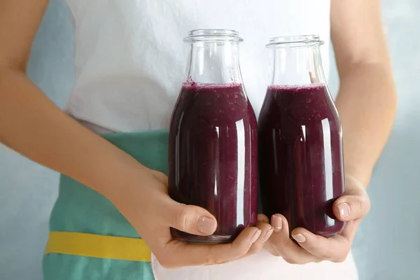 Mujer sosteniendo botellas de vidrio con jugo de acai, primer plano — Foto de Stock