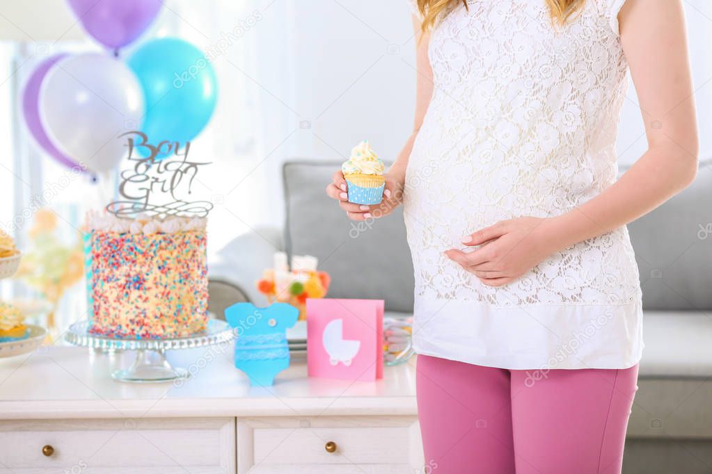 Pregnant woman holding cupcake at baby shower party