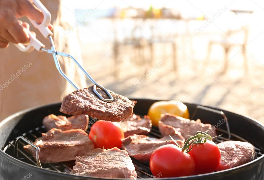 Man cooking steaks and vegetables on barbecue grill