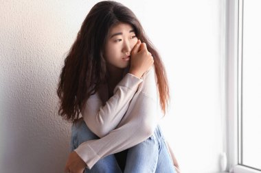 Duvara yakın oturan üzgün genç kadın