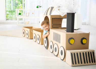 Küçük çocuk ışık odada karton tren ile oynarken
