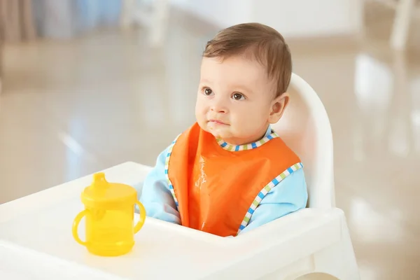 Bebê bonito com garrafa de água sentado na cozinha — Fotografia de Stock