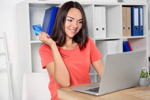 Mujer joven usando el ordenador portátil mientras sostiene la tarjeta de crédito en casa. Concepto de compras por Internet — Foto de Stock