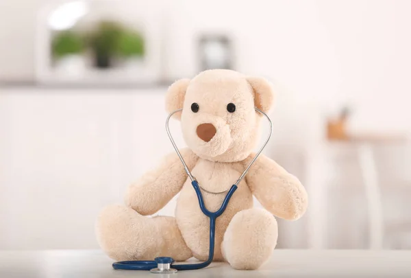 Lindo oso de peluche con estetoscopio en la mesa en el interior — Foto de Stock