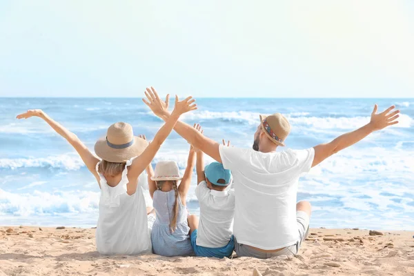 Joyeux famille assis sur la plage de la mer à la station — Photo