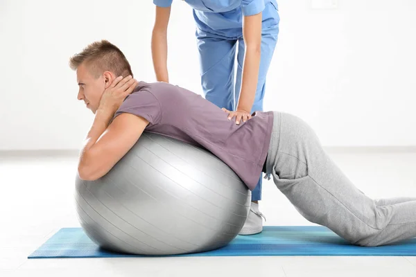 Fysiotherapeut werken met jonge mannelijke patiënt in kliniek — Stockfoto