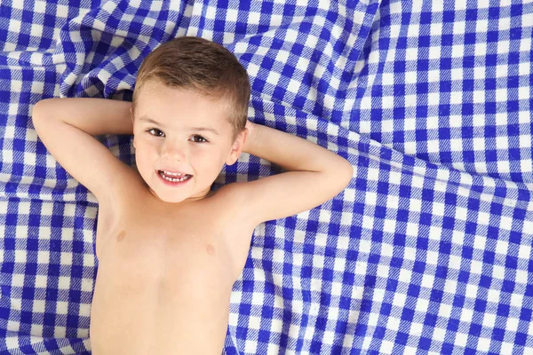 Roztomilý malý chlapec leží na pestré plážový ručník — Stock fotografie