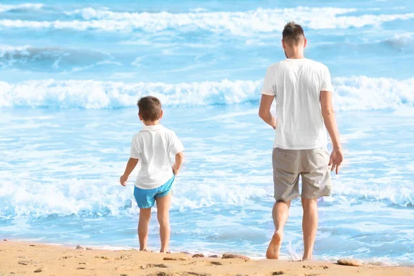 Симпатичный мальчик с отцом на морском пляже на курорте — стоковое фото
