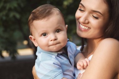 Güzel genç anne holding şirin bebek çocuk, açık havada