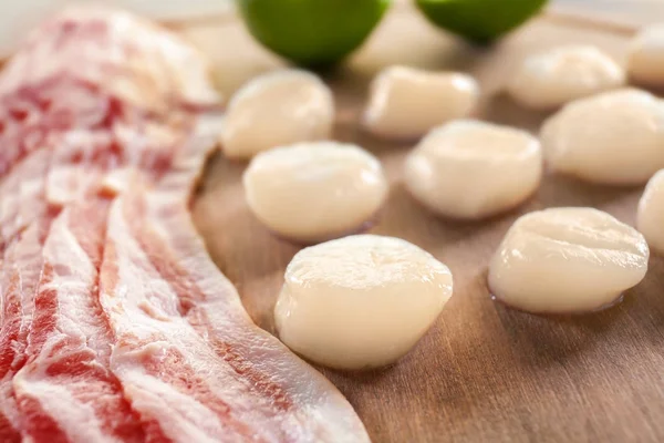 Wooden board with raw bacon and scallops — Stock Photo, Image