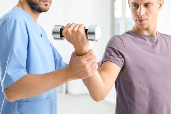 Fysiotherapeut werken met jonge mannelijke patiënt in kliniek — Stockfoto