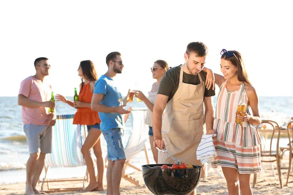 Young people having barbecue party on beach