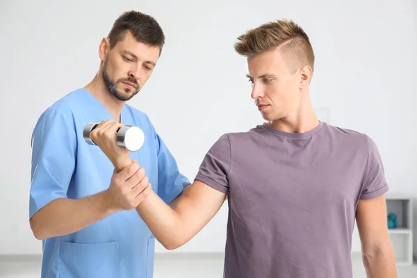 병원에서 젊은 남성 환자와 함께 작동 하는 물리 요법가 — 스톡 사진