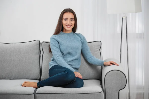 Молода жінка на дивані вдома — стокове фото
