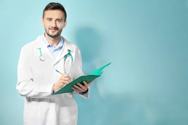 Manlig läkare med Urklipp på färgbakgrund — Stockfoto