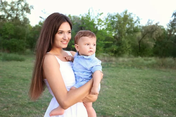Beautiful young mother holding cute baby boy, outdoors — Stock Photo, Image