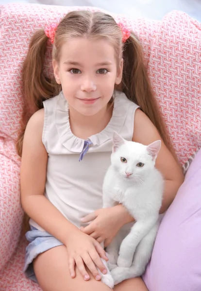 Meisje zittend in fauteuil met witte kat binnenshuis — Stockfoto