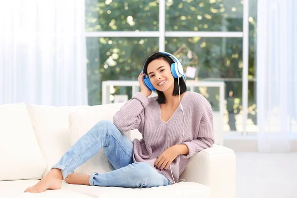 Giovane donna che ascolta musica attraverso le cuffie a casa — Foto Stock