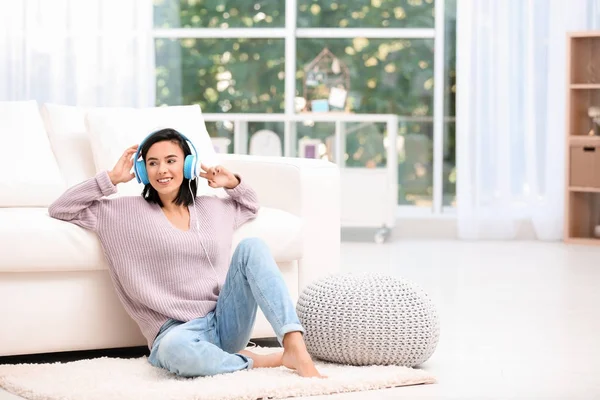 Молода жінка слухає музику через навушники вдома — стокове фото