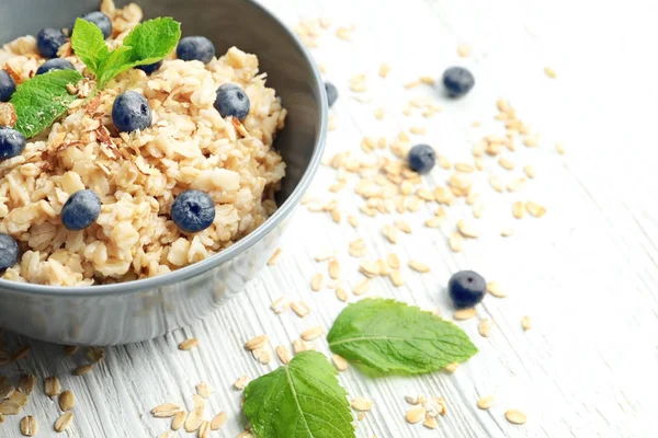 Leckere Haferflocken mit Beeren in Schüssel auf dem Tisch — Stockfoto