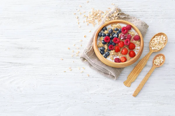 Tasty oatmeal with berries in bowl on table