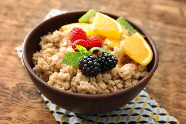 Tasty oatmeal with berries and fruit in bowl on table — Stock Photo, Image