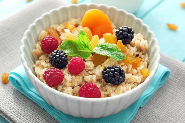 Leckere Haferflocken mit Beeren und Früchten in Schüssel auf dem Tisch — Stockfoto